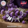 BTS Purple I Purple You Charm Bracelet with logo, microphone, and number 7 charms on a silver chain over purple flowers.
