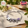 BTS Purple I Purple You charm bracelet with silver chain, BTS logo, number 7, microphone charms, and heart on linen cloth.