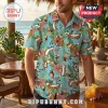Man wearing a light blue tropical Hawaiian shirt featuring a repeating pattern of Calvin and Hobbes characters and hibiscus.!