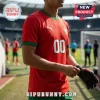 Athlete wearing red Portugal soccer jersey with green trim and number 00 on the chest, standing on a grass pitch.!