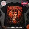 David Bowie Halloween Costume 2026 T-Shirt featuring Bowie with lightning bolt makeup, jack-o'-lantern, and graveyard scene.