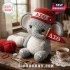 Crocheted gray elephant plushie wearing a red hat with Delta Sigma Theta Greek letters and holding a matching pennant.!