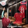 Cristiano Ronaldo wearing a red Portugal soccer jersey inside a locker room with a Diogo J. 21 kit hanging behind him.!