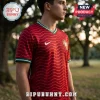 Man wearing red Portugal national football jersey with wavy lines, green collar trim, and white Nike logo outdoors.!