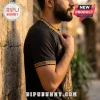 Man wearing black t-shirt with gold Greek key pattern on collar and sleeves and 2026 text printed on chest.!