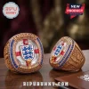 England national football team 154th anniversary gold championship rings with blue gemstones and team crests on wood table.!