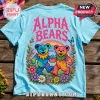 Light blue t-shirt with Alpha Bears text, two tie-dye teddy bears, rainbow, and floral border graphic on wooden surface.!