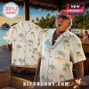 Short-sleeve button-up tropical Hawaiian shirt featuring palm trees and beach huts on a white background.!