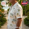 Man wearing a cream-colored short-sleeve button-down shirt featuring a repeating tropical palm tree and beach hut pattern.!