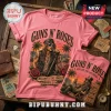 Pink cotton t-shirt with Guns N' Roses rock band graphic of Axl Rose, palm trees, roses, and song titles on wooden table.!