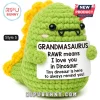 Green crochet dinosaur plush with yellow spikes holding a sign reading Grandmasaurus Rawr means I love you in Dinosaur.!