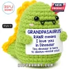 Green crochet dinosaur plushie with yellow spikes holding a sign that says Grandpasaurus Rawr means I love you.!