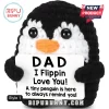 Black and white crocheted penguin amigurumi holding a white sign with black text reading Dad I Flippin Love You.!