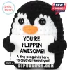 Black and white crocheted penguin plush holding a white sign that reads YOU'RE FLIPPIN AWESOME! on a white background.!