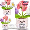 Crochet potted plant with pink, purple, and white yarn flowers, featuring a smiling face and a sign saying I Love You.!