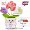 Crocheted potted plant toy with pink, purple, and white flowers, holding a card that reads Never Forget the Difference.!