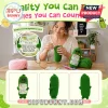Crochet green pickle plush with sunglasses and attached encouragement card sitting on a wooden table with yarn and hooks.!