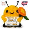 Yellow crochet bee plush holding an orange flower and a white sign reading Positive Bee with motivational text.!