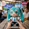 Hatsune Miku plush toy wearing an Argentina number 10 soccer jersey held by hands at a bar with blurry background fans.!
