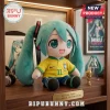 Hatsune Miku plush toy wearing a yellow Brazil soccer jersey number 11 seated on a wooden display shelf.!