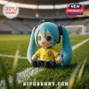 Hatsune Miku plush toy wearing a yellow Brazil national football team jersey with number 11 on a stadium grass field.!