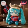 Plush Hatsune Miku figure wearing a Viking helmet and a red Norway soccer jersey with number 9 on a wooden shelf.!