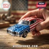 Die-cast muscle car model with American flag paint, stars on hood, stripes on roof, held by hand over wooden surface.!