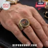 Gold Iron Maiden 50th anniversary ring with central 50 numeral and circular character emblems on a man's finger.!
