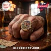Gold Iron Maiden 50th anniversary championship ring on a tattooed hand with beer glasses and concert tickets on a table.!