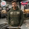 Man wearing a distressed olive green Jeep 85th Anniversary hoodie with graphic text and mountain vehicle illustration.!