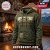 Olive green Jeep 85th anniversary hooded sweatshirt with vintage graphics on a rustic wooden chair by a fireplace.!