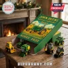 John Deere 2025 advent calendar box with miniature green and yellow tractor ornaments on a wooden table near a fireplace.!