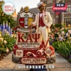 Kappa Alpha Psi fraternity statue in cream suit and fedora with Greek crest, cane, and floral base on outdoor stone path.!