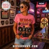 Woman wearing pink Kiss band graphic t-shirt with palm trees and sun background, standing in a rock-themed vintage bar.!