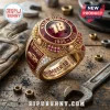 Kyle Busch commemorative gold championship ring with red center, number 18, and racing motifs on a wooden workbench surface.!