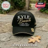 Black baseball cap featuring gold and white Kyle Busch embroidery, 18 racing number, and champion text on stone surface.!