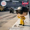 Kyle Busch M&M's racing vinyl figure wearing sunglasses and a cap, standing on a concrete wall at a NASCAR track.!