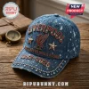 Acid-wash blue baseball cap with red rhinestone Liverpool logo, metal stars, and 1892-2026 text on a wooden surface.!