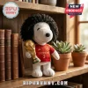 Marc Cucurella Spain Snoopy plush toy wearing a number 3 red jersey and holding a gold World Cup trophy on a wooden shelf.