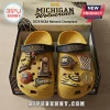 Yellow foam clogs with Michigan Wolverines basketball charms, trophy, championship ring, and sneakers in a branded box.!