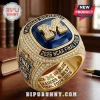 Michigan Wolverines gold championship ring with blue stone, diamond pavé, and 2026 NCAA Final Four text on a wood desk.!