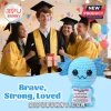 Blue crocheted axolotl plush holding a sign with motivational text about bravery in front of four smiling graduates.!