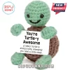 Small handmade green and brown crochet turtle plush holding a sign that says You are Turtle-y Awesome on white background.!