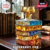 Stack of colored glass books shaped decanter with a small open book topper sitting on a dark wooden desk.!
