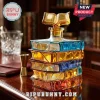Stack of colored glass books shaped decanter with an open book stopper sitting on a dark wood desk.!