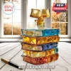 Stack of colored glass books shaped decanter with an open book stopper sitting on a wooden table near a fountain pen.!