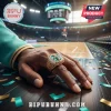 Gold championship ring with green center stone on a hand over basketball court floor with confetti.!