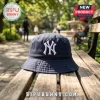New York Yankees Embroidered Logo Bucket Hat in navy blue cotton fabric with a white stitched emblem on a wooden bench.