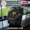 Newcastle United 135-year anniversary black stainless steel wristwatch with gold crest and dial against a stadium backdrop.!