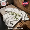 White Oakland Athletics baseball jersey with green and yellow Athletics logo, number 94, and BTS logo on a wood table.!